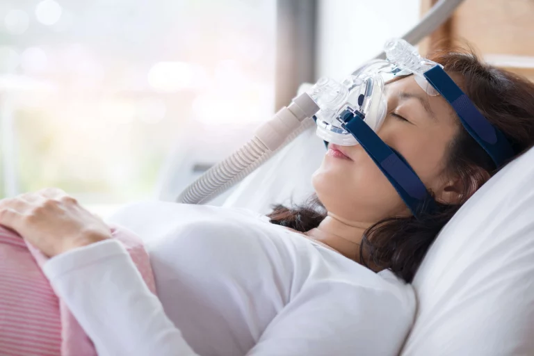 Frau mit CPAP-Maske im Krankenhausbett